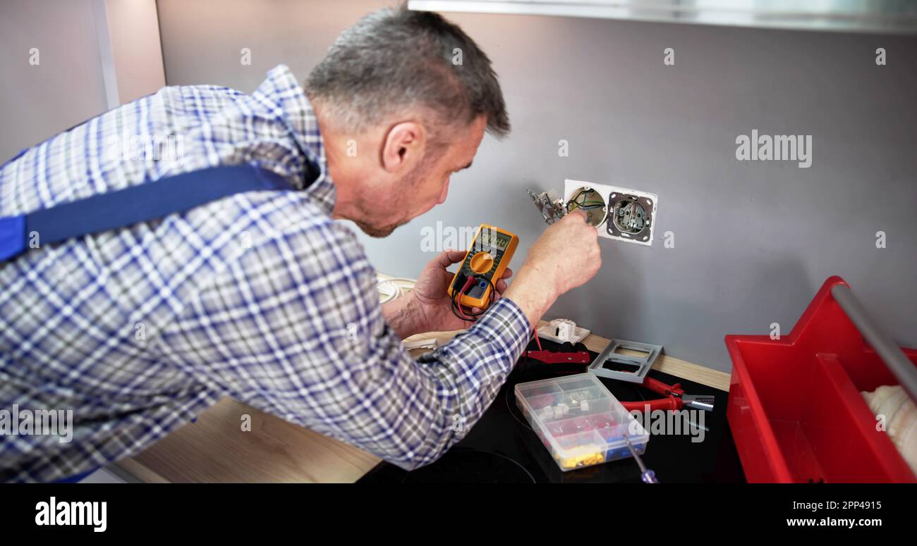 Close-up Of Person Hand Metering Socket Voltage With Digital Multimeter Banque D'Images