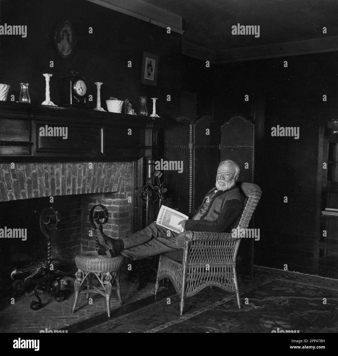 Andrew Carnegie dans son chalet de golf Neaer St. Andrew's Golf Links, comté de Westchester, New York, assis dans une chaise en osier tenant le maga indépendant Banque D'Images