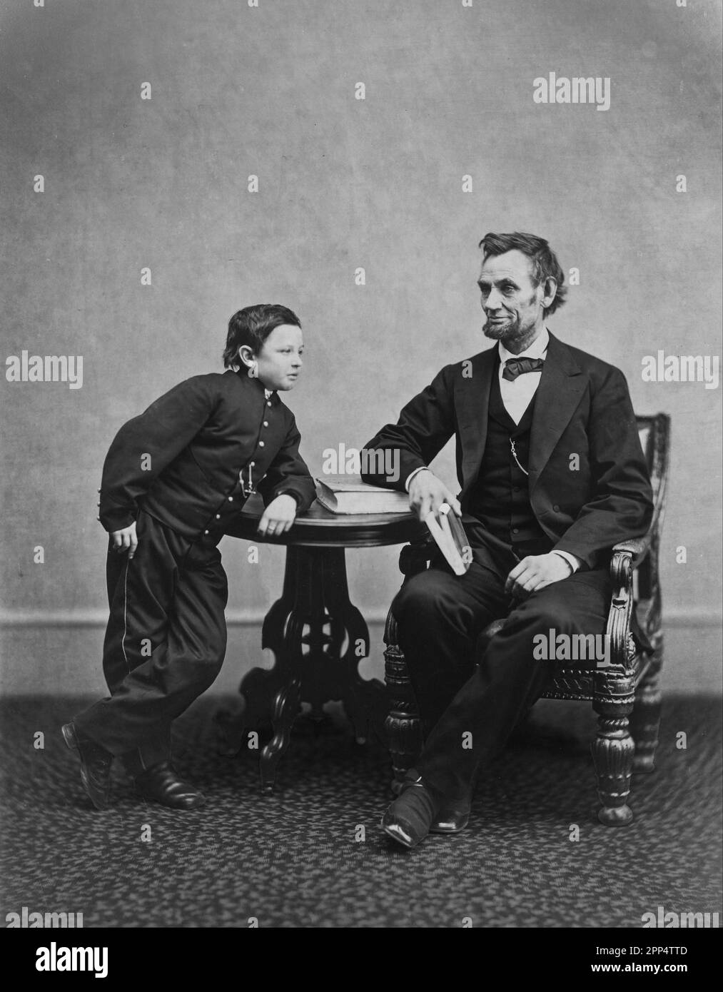 Abraham Lincoln, assis et tenant un livre, avec son fils TAD (Thomas) appuyé sur une table. 5th févr. 1865. Photographe: Alexander Gardner Banque D'Images