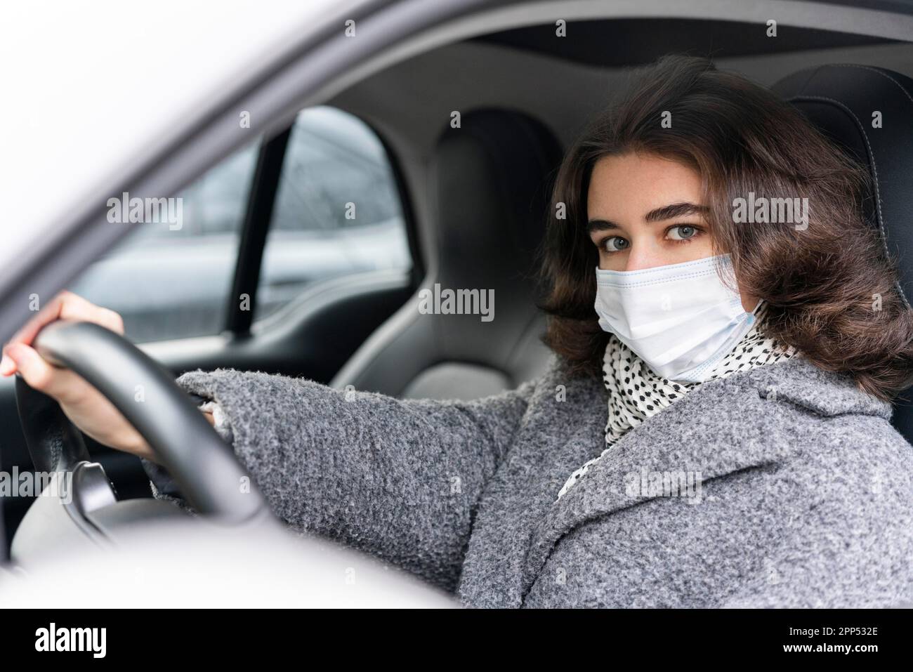 Femme avec masque médical conduisant la voiture Banque D'Images