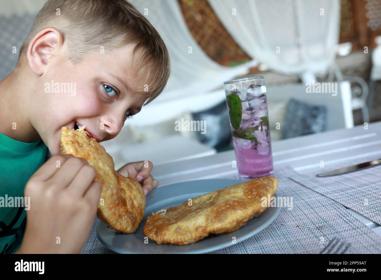 Un garçon affamé mangeant un cheburek dans un restaurant Banque D'Images