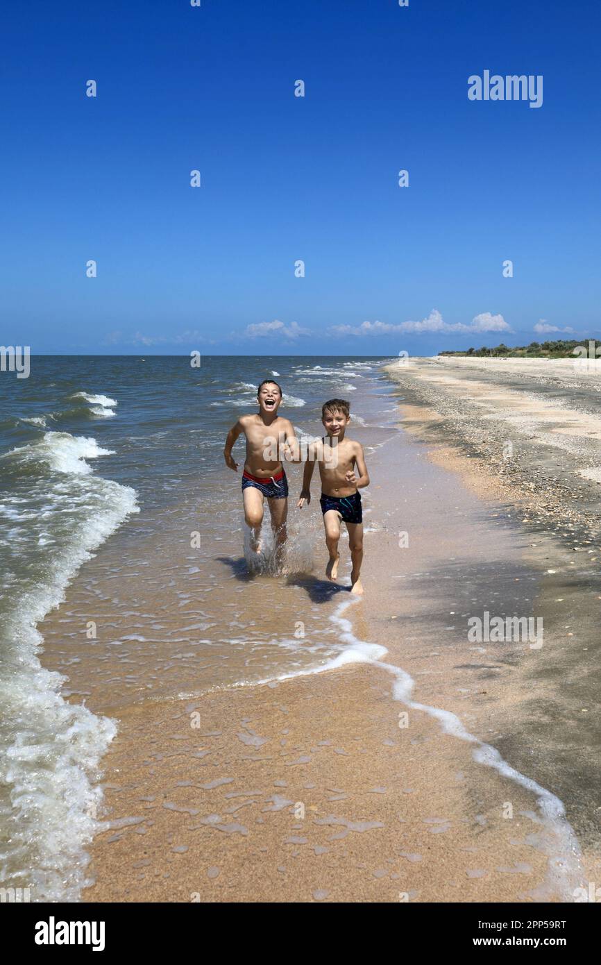 Frères longeant la plage de la mer d'Azov, Primorsko-Akhtarsk Banque D'Images