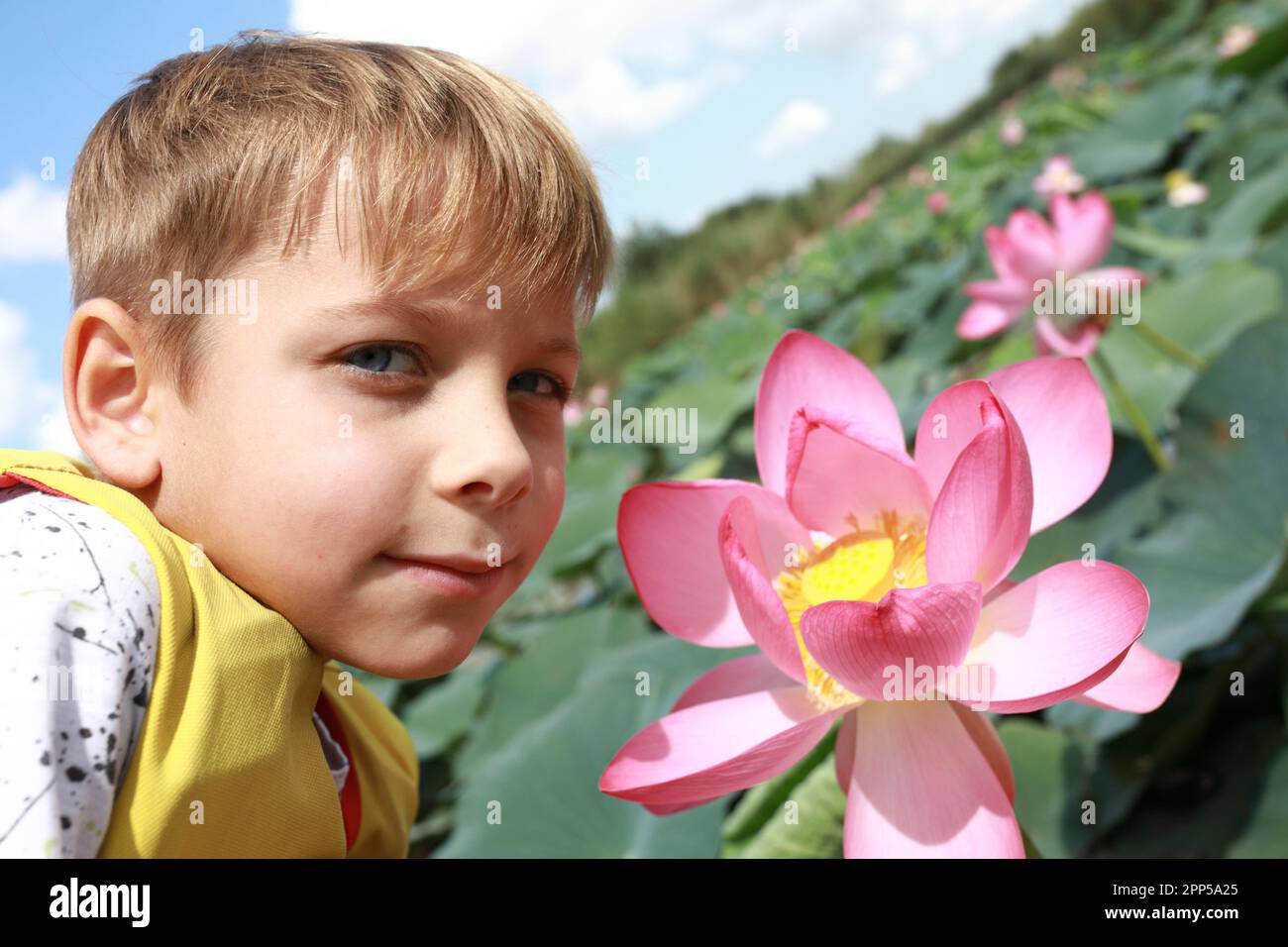 Enfant posant avec la fleur de lotus indien dans l'estuaire de la mer d'Azov, Primorsko-Akhtarsk Banque D'Images