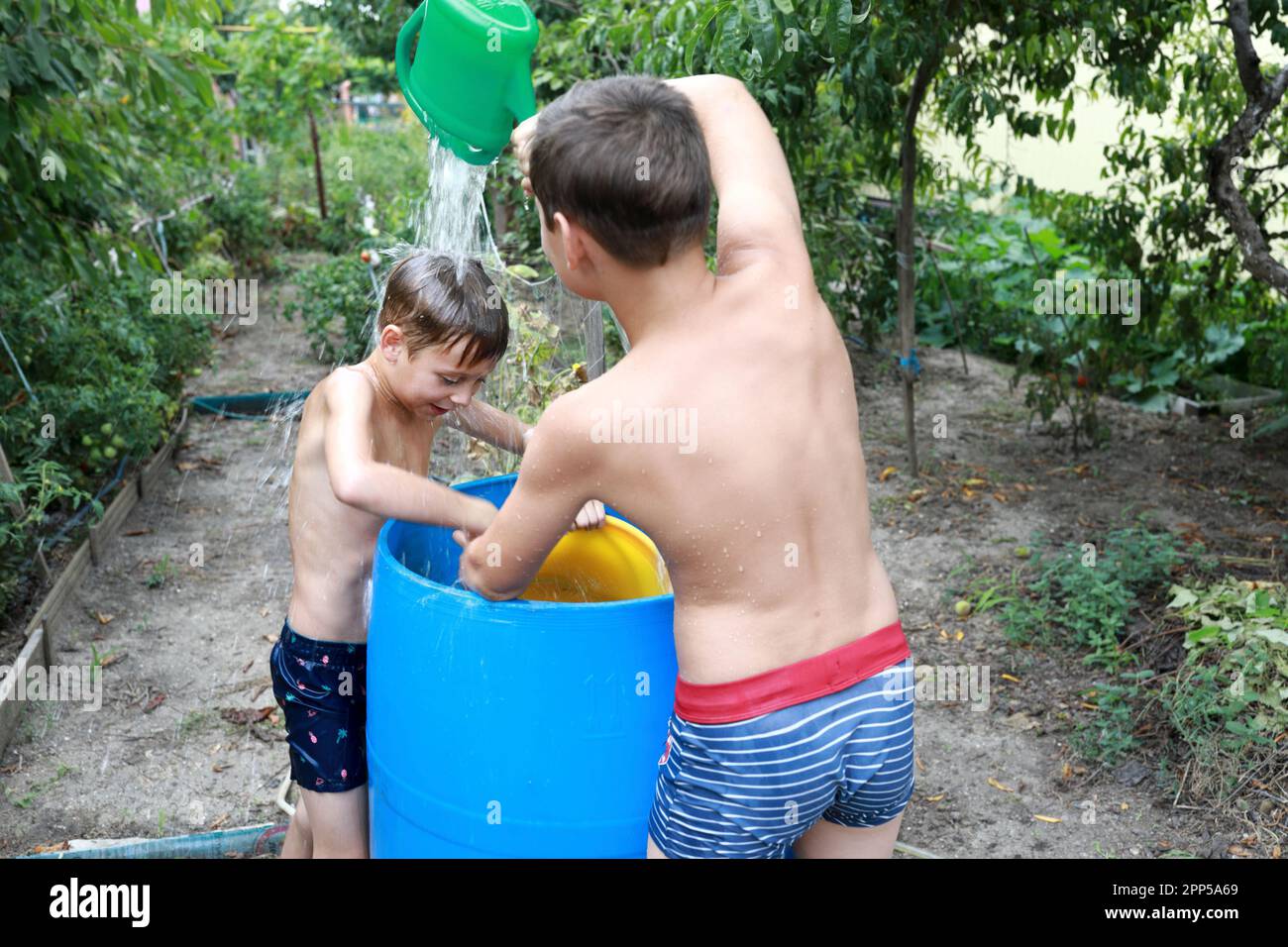 En été, les enfants se versent de l'eau les uns sur les autres dans la cour Banque D'Images