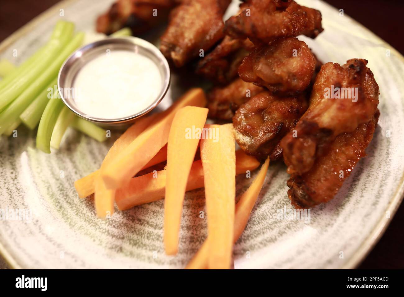 Ailes de poulet frites avec bâtonnets de légumes sur l'assiette au pub Banque D'Images