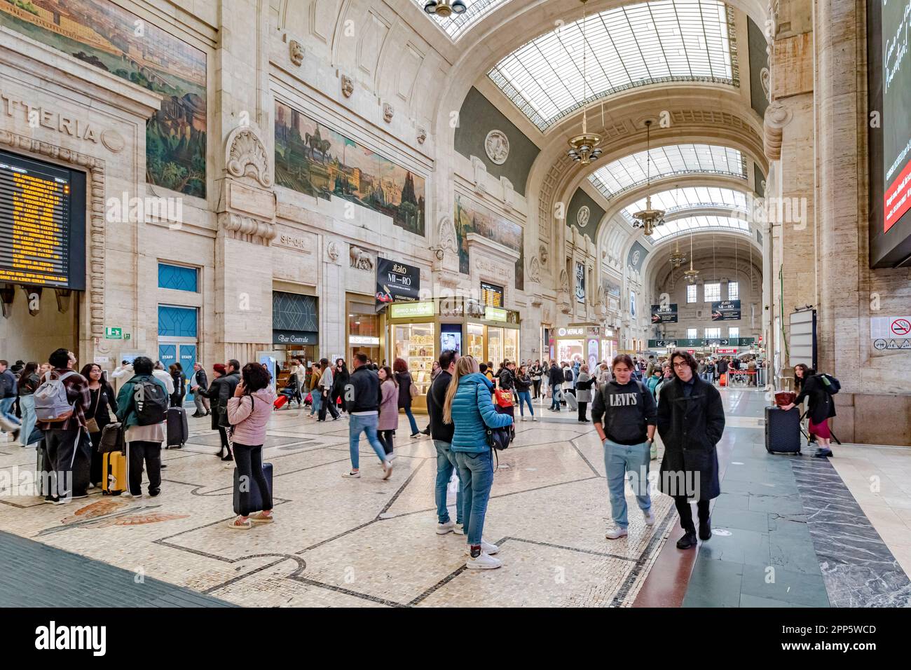 Personnes marchant à travers l'intérieur magnifique du hall d'entrée au rez-de-chaussée de la gare centrale de Milan, en Italie Banque D'Images