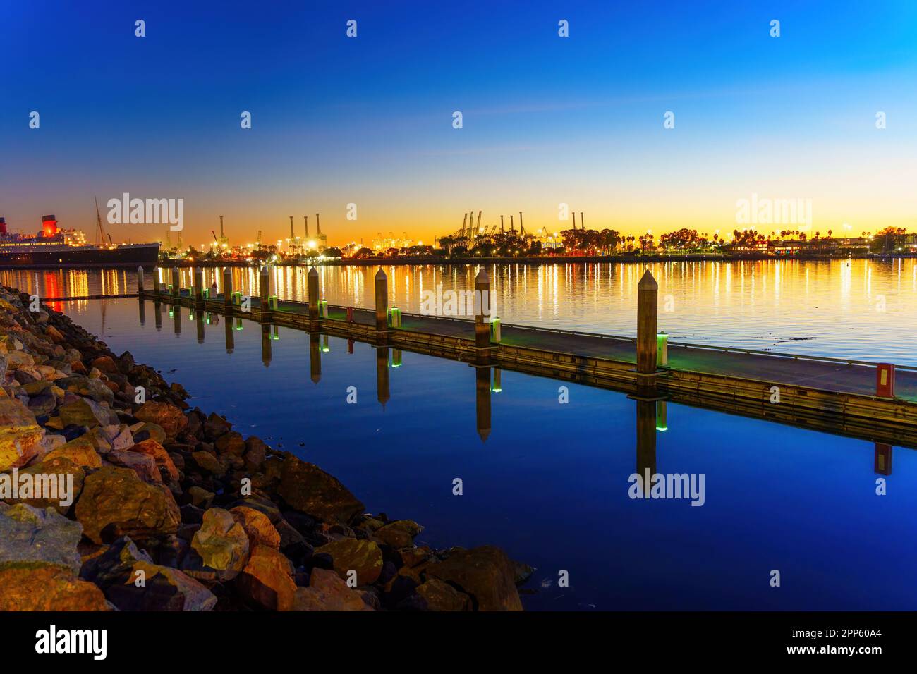 Beauté illuminée du port de long Beach la nuit, avec le légendaire bateau Queen Mary et son reflet dans l'eau ajoutant au paysage urbain à couper le souffle Banque D'Images