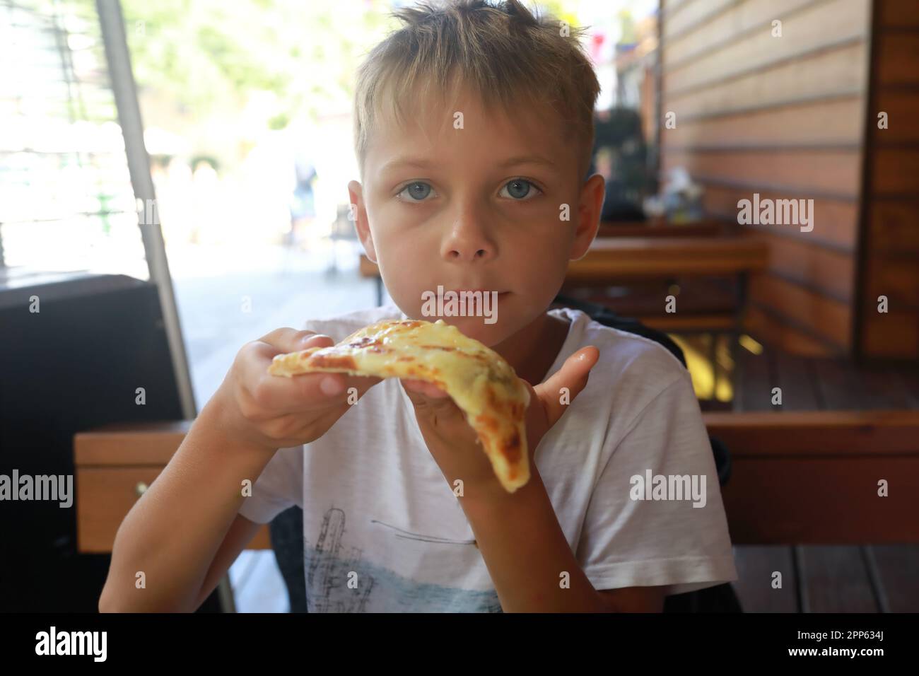 Un enfant mange quatre pizzas au fromage dans le restaurant Banque D'Images