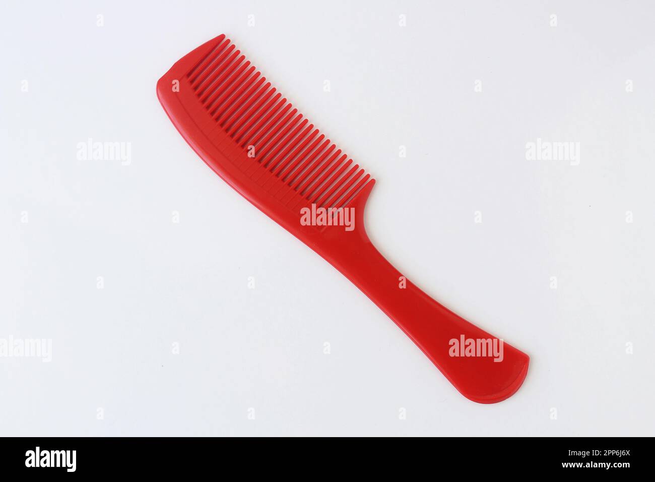 Vue de dessus sur la brosse à cheveux en plastique rouge isolée sur fond blanc. Banque D'Images