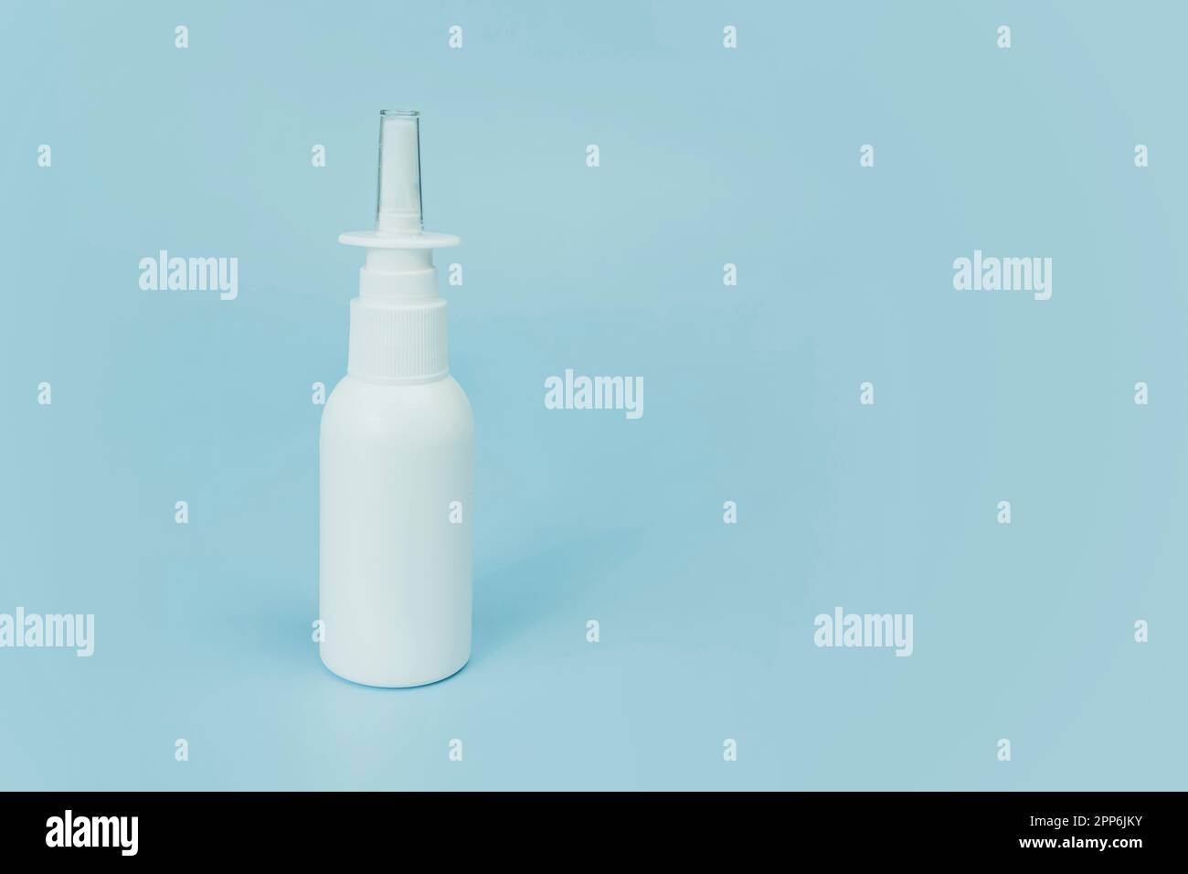 Flacon vaporisateur nasal sur fond bleu avec espace de copie. Flacon pulvérisateur médical en plastique blanc, gros plan. le concept de médecine de santé et de pharmacie. Prod Banque D'Images