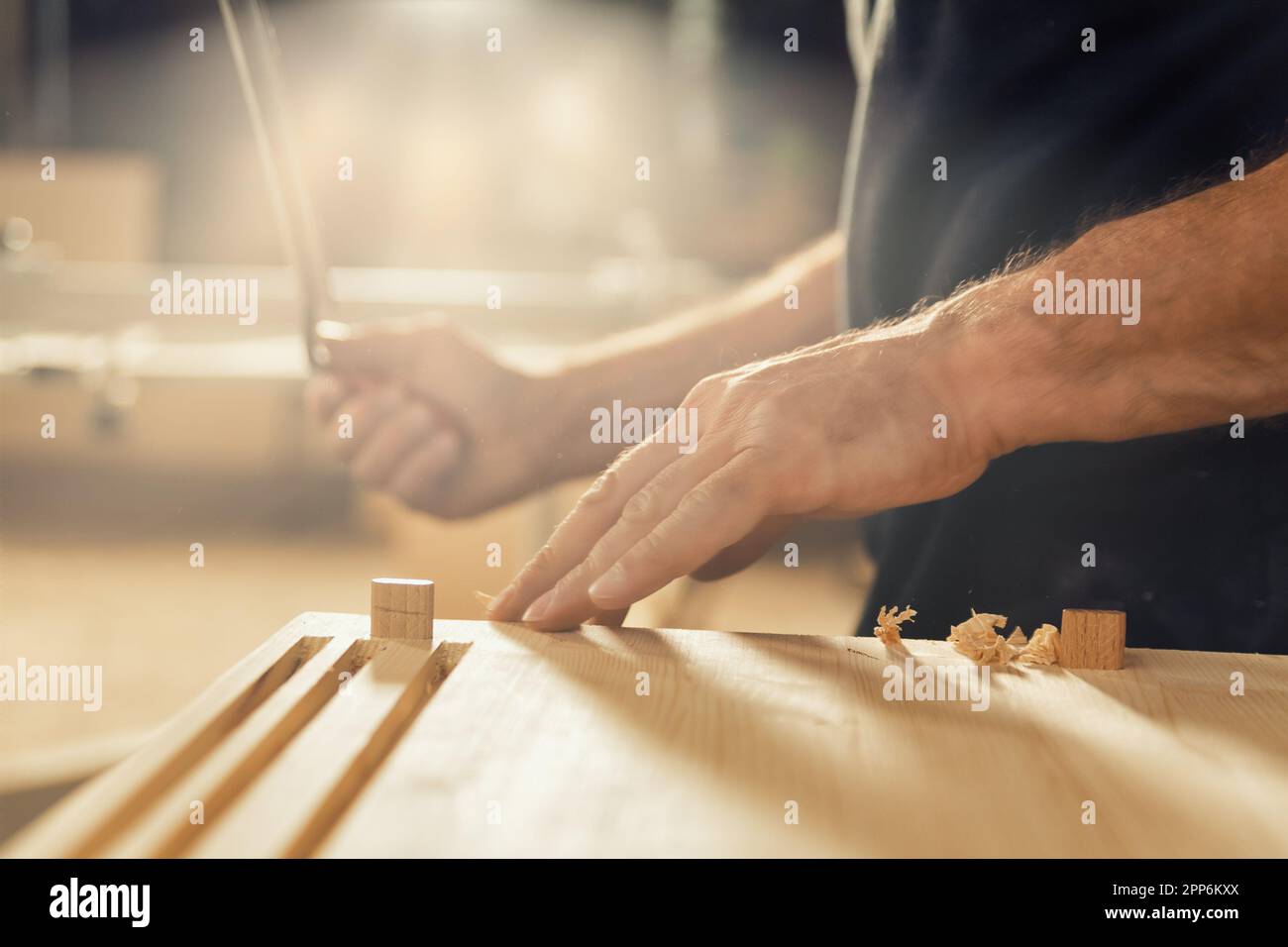 Un artisan se tient avec son couteau à la main. Ce charpentier aime utiliser son outil de coupe manuel parce qu'il désire le contrôle et la capacité de compter s Banque D'Images