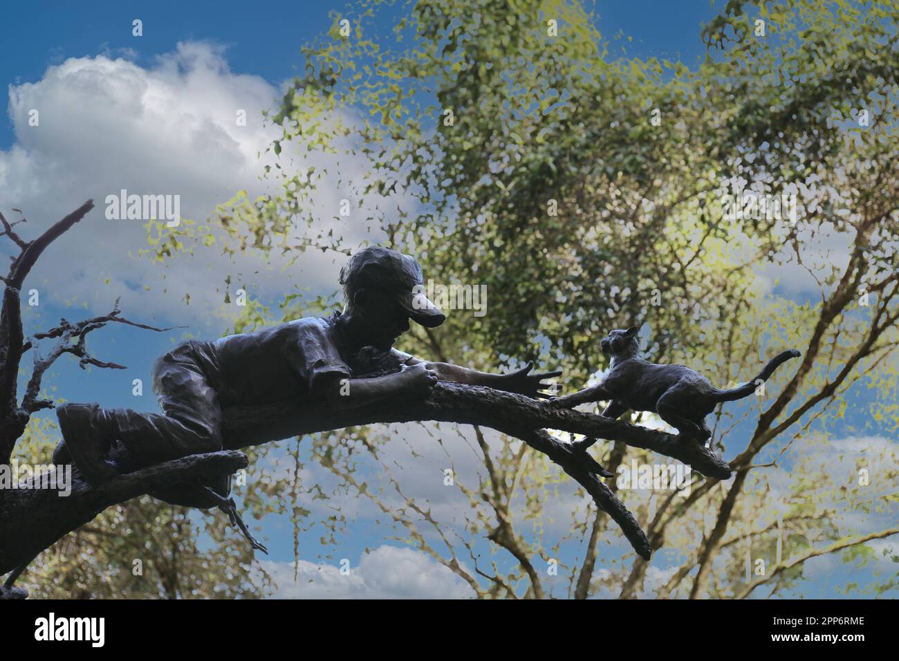 Gros plan d'une sculpture d'un jeune garçon sauvant un chat d'un arbre, avec un fond abstrait, intitulé The Rescue at Na Aina Kai Botanical Gardens a Banque D'Images