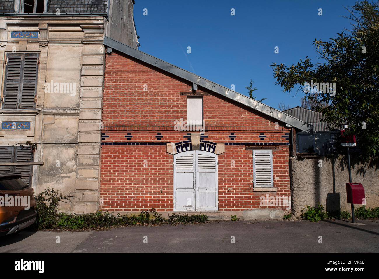 Façade d'une ancienne petite maison en brique rouge avec volets en bois blanc Banque D'Images