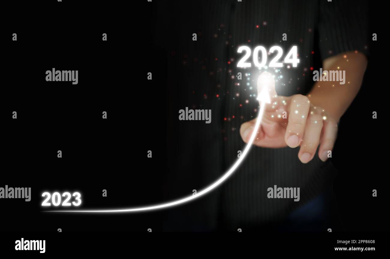 Le doigt d'un homme trace une ligne courbe vers le haut de 2023 à 2024. Nouvel an, Noël, démarrage, nouvelle entreprise, définition d'un objectif personnel Banque D'Images