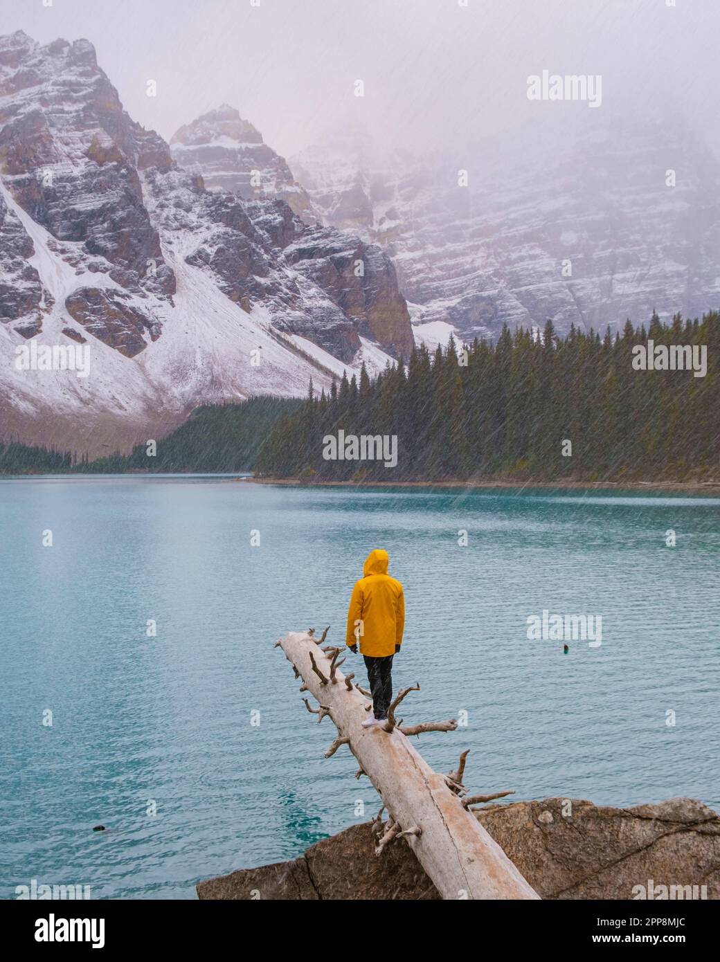 Lac Moraine pendant une journée de neige froide en automne au Canada, de belles eaux turquoise du lac Moraine avec de la neige. couple d'hommes et de femmes en blousons de pluie jaunes pendant la neige Banque D'Images