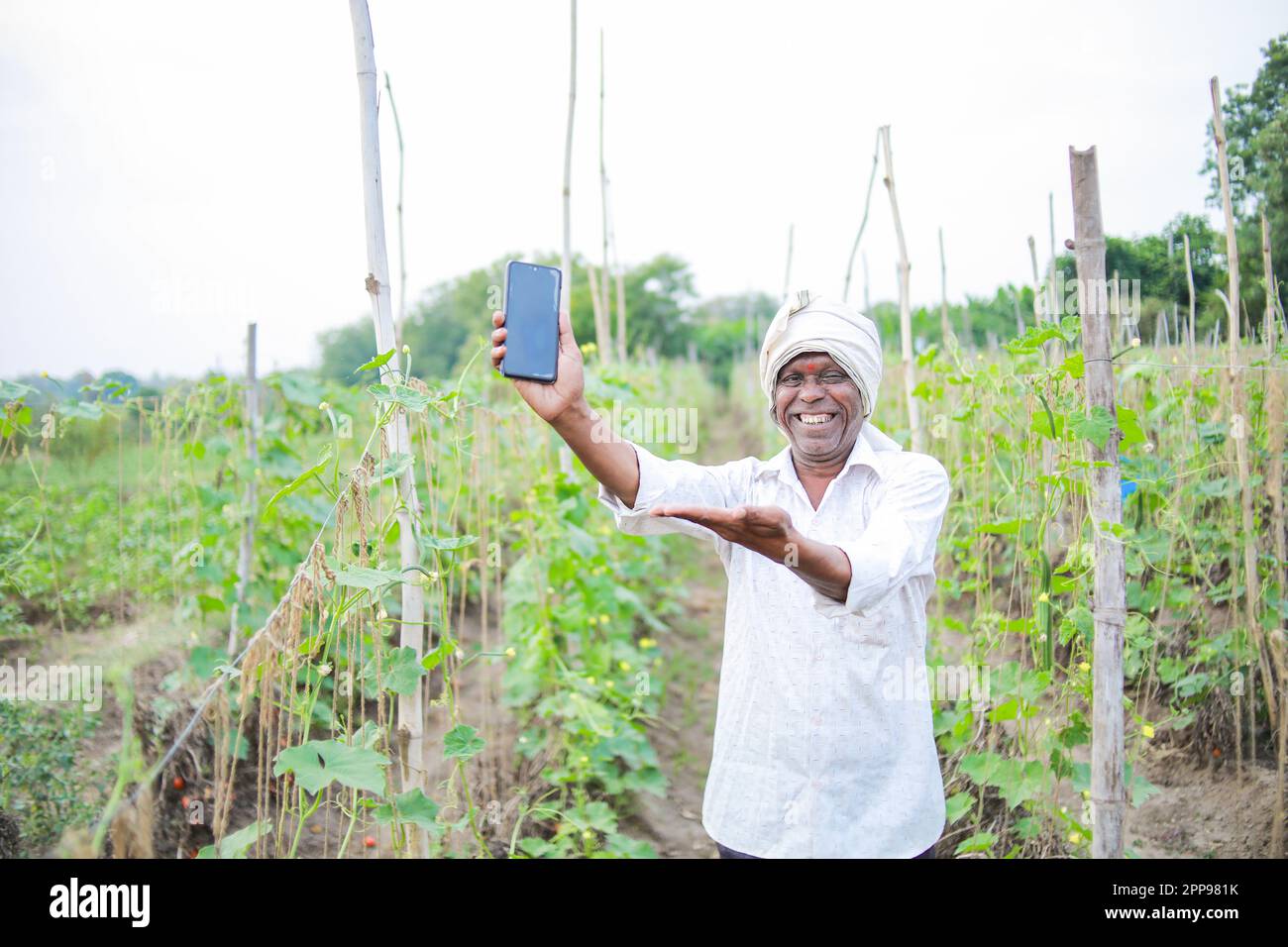 Un fermier indien heureux tenant mobile à la main Banque D'Images