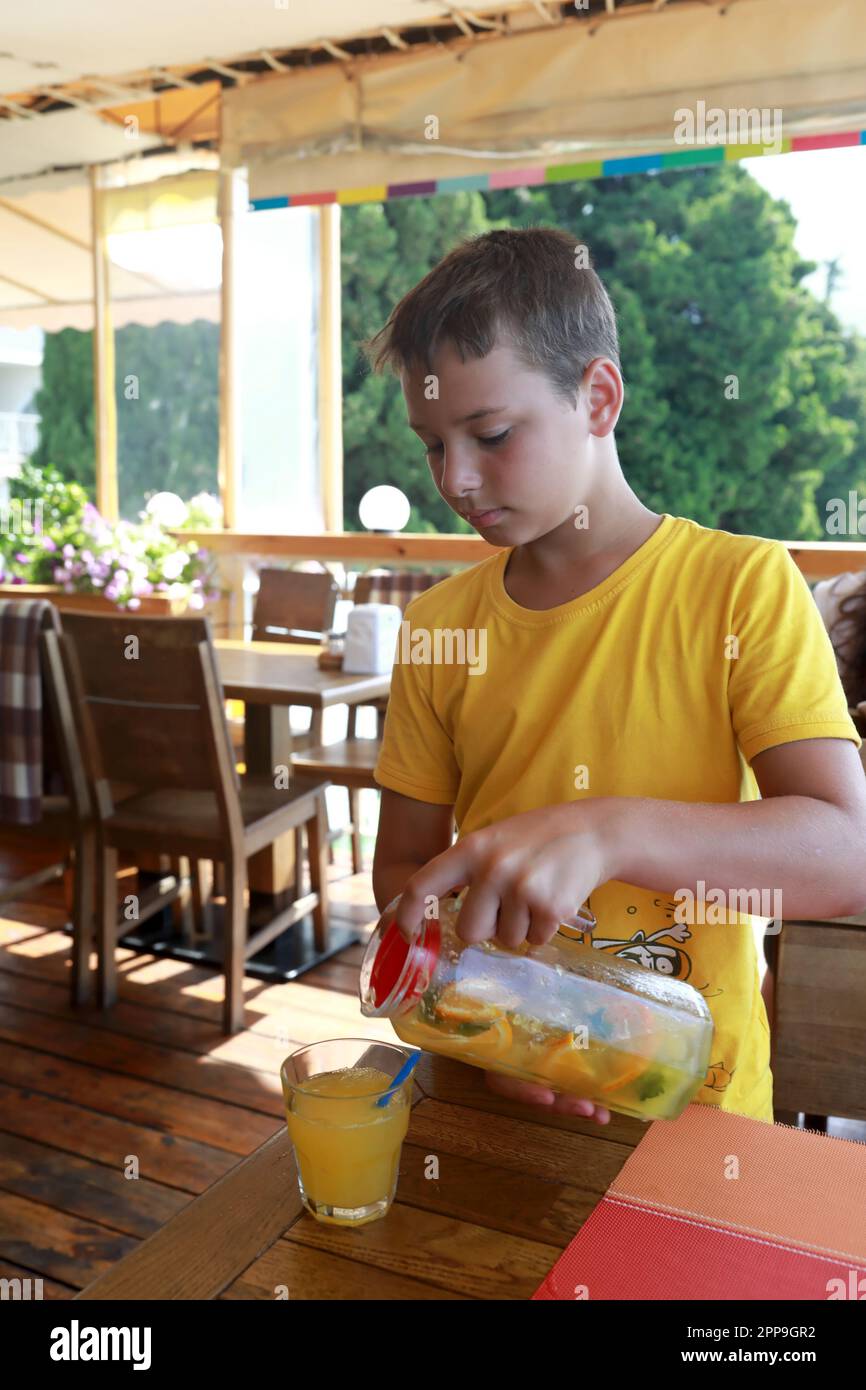 Enfant versant du jus du pichet dans le verre du restaurant Banque D'Images