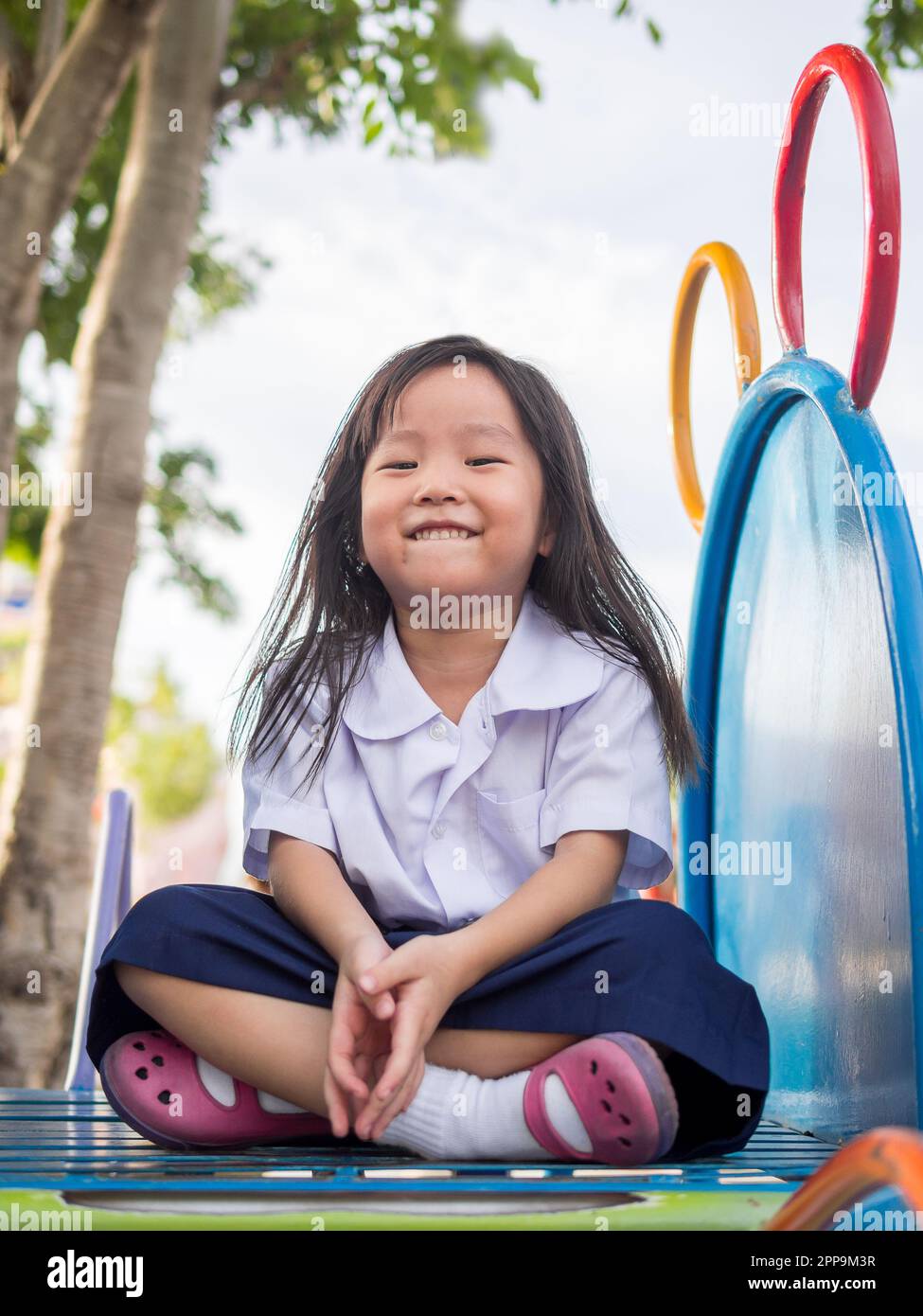 Joyeux enfant, enfant asiatique en uniforme scolaire jouant sur le terrain de jeu Banque D'Images