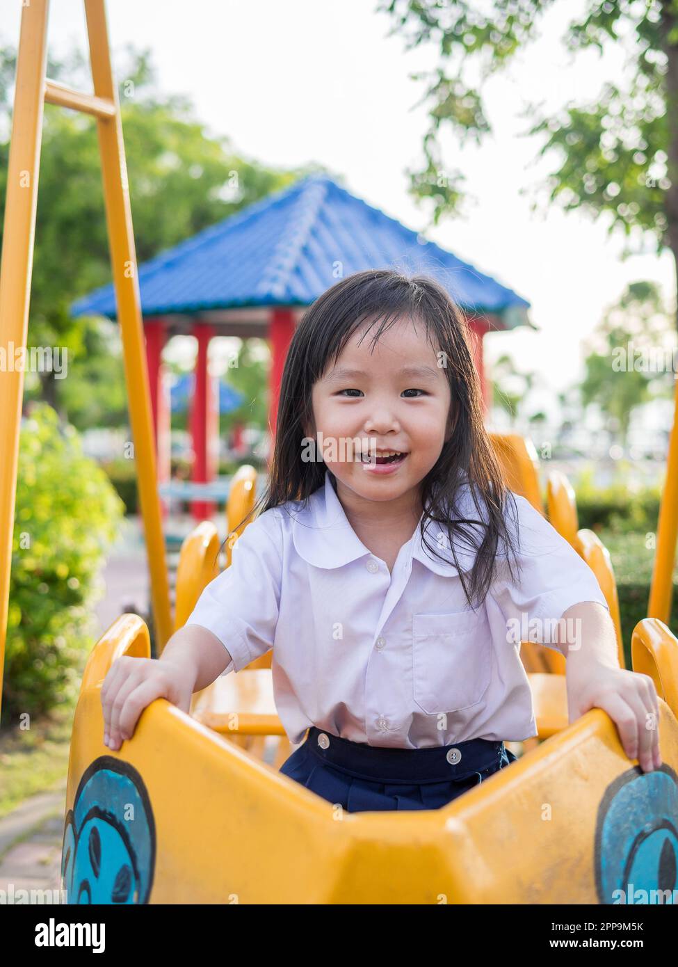 Joyeux enfant, enfant asiatique en uniforme scolaire jouant sur le terrain de jeu Banque D'Images