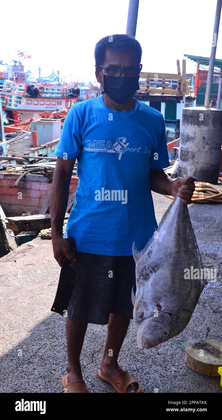 Un homme tient un gros poisson pêché dans le port de la rivière Rayong, province de Rayong, Thaïlande, Asie du Sud-est. Rayong est une ville sur la côte est du golfe de Thaïlande et la capitale de la province de Rayong. La pêche est une industrie importante dans ce domaine. Banque D'Images