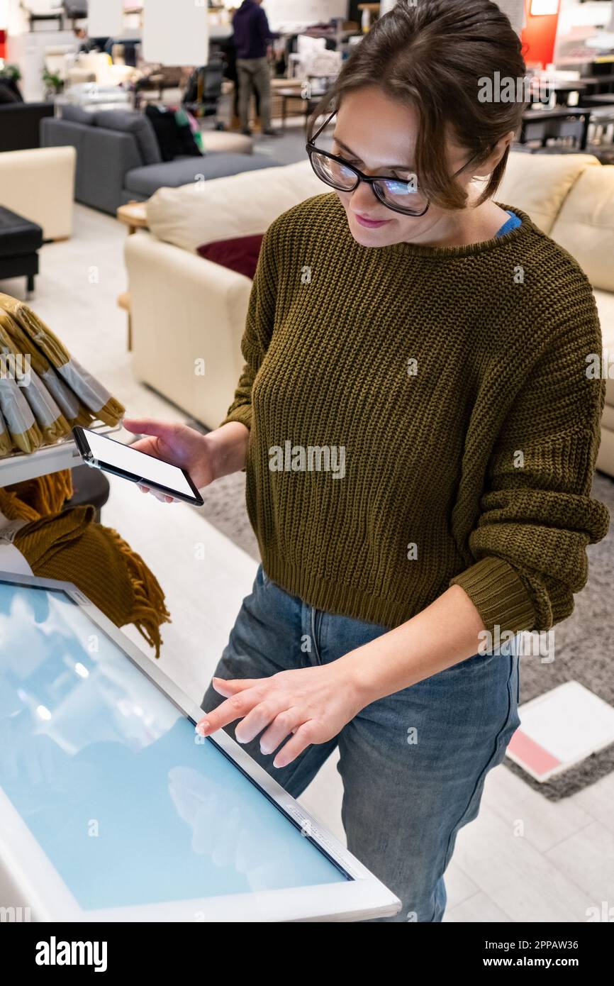 Une femme au téléphone utilise un kiosque en libre-service dans le centre commercial. Photo de haute qualité Banque D'Images