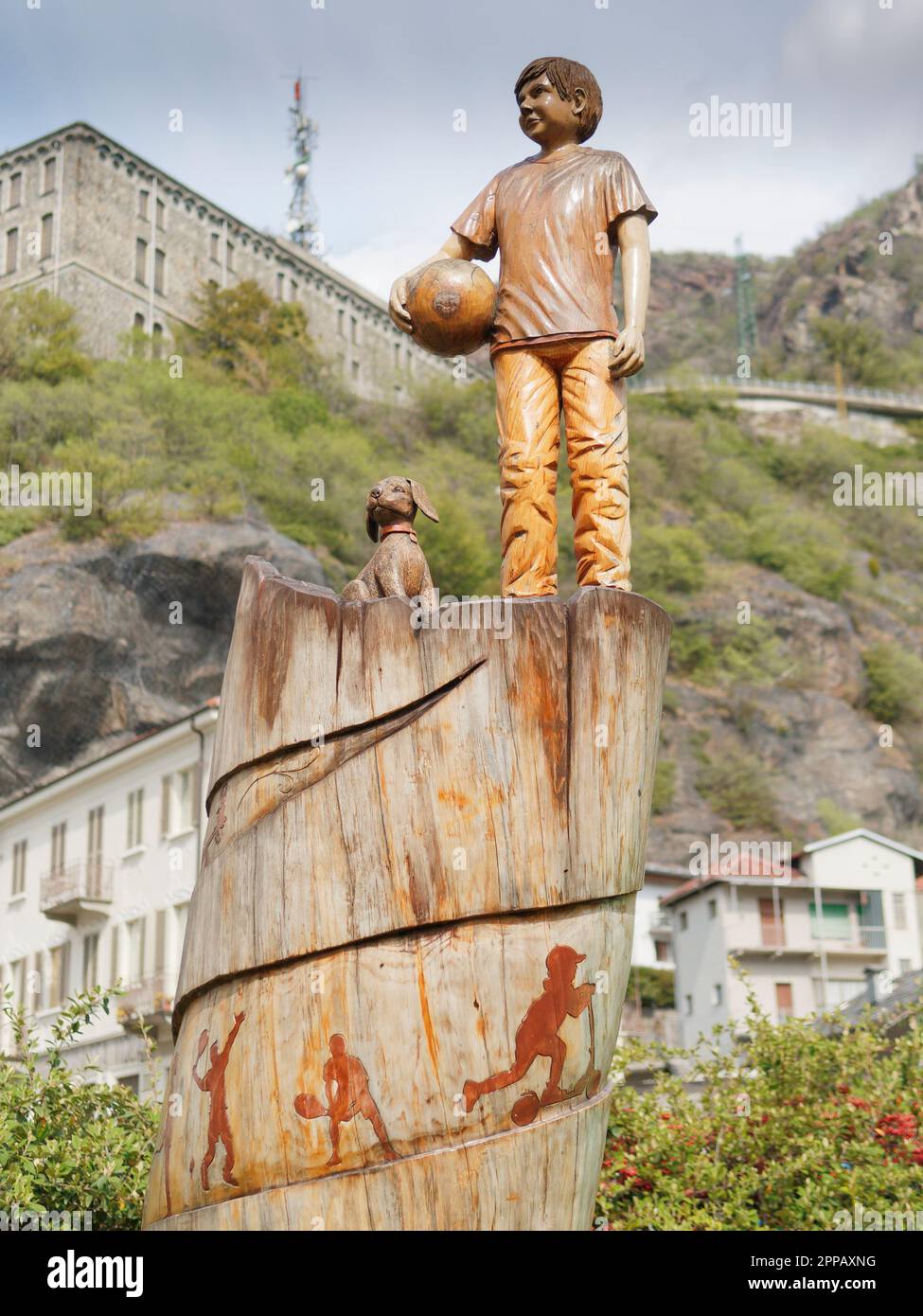 Statue en bois d'un garçon avec une balle et un chien dans un parc dans la ville de Pont-Saint-Martin, Vallée d'Aoste, NW Italie Banque D'Images