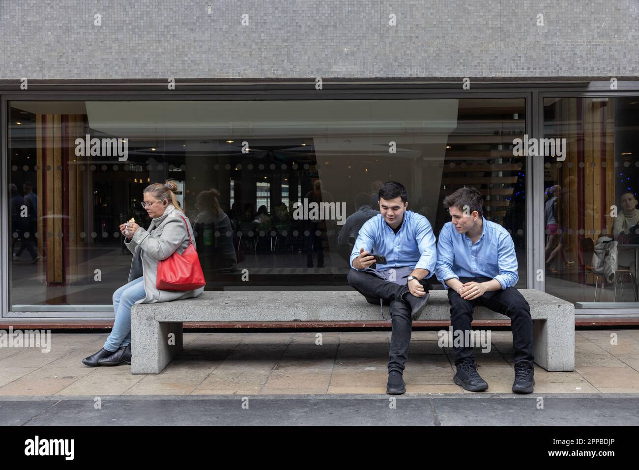 Les gens s'assoient sur un banc de béton à l'extérieur du Royal Festival Hall, Southeast Bank London pendant leur pause déjeuner, Londres, Angleterre, Royaume-Uni Banque D'Images
