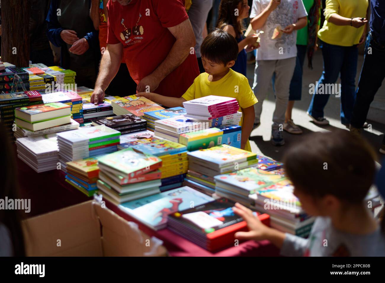 Barcelone, Espagne. 23rd avril 2023. Les enfants sont vus acheter des livres dans une cabine pendant la fête catalane traditionnelle de Saint George's Day. Ce jour-là, connu sous le nom de « jour de Saint-Georges » (Diada de Sant Jordi en catalan), l'amour et la littérature sont célébrés par la vente de livres et de roses rouges dans tout le pays. Depuis l'année 1997, le slogan officiel de ce jour a été "Une rose pour l'amour, et un livre pour toujours". Crédit : SOPA Images Limited/Alamy Live News Banque D'Images