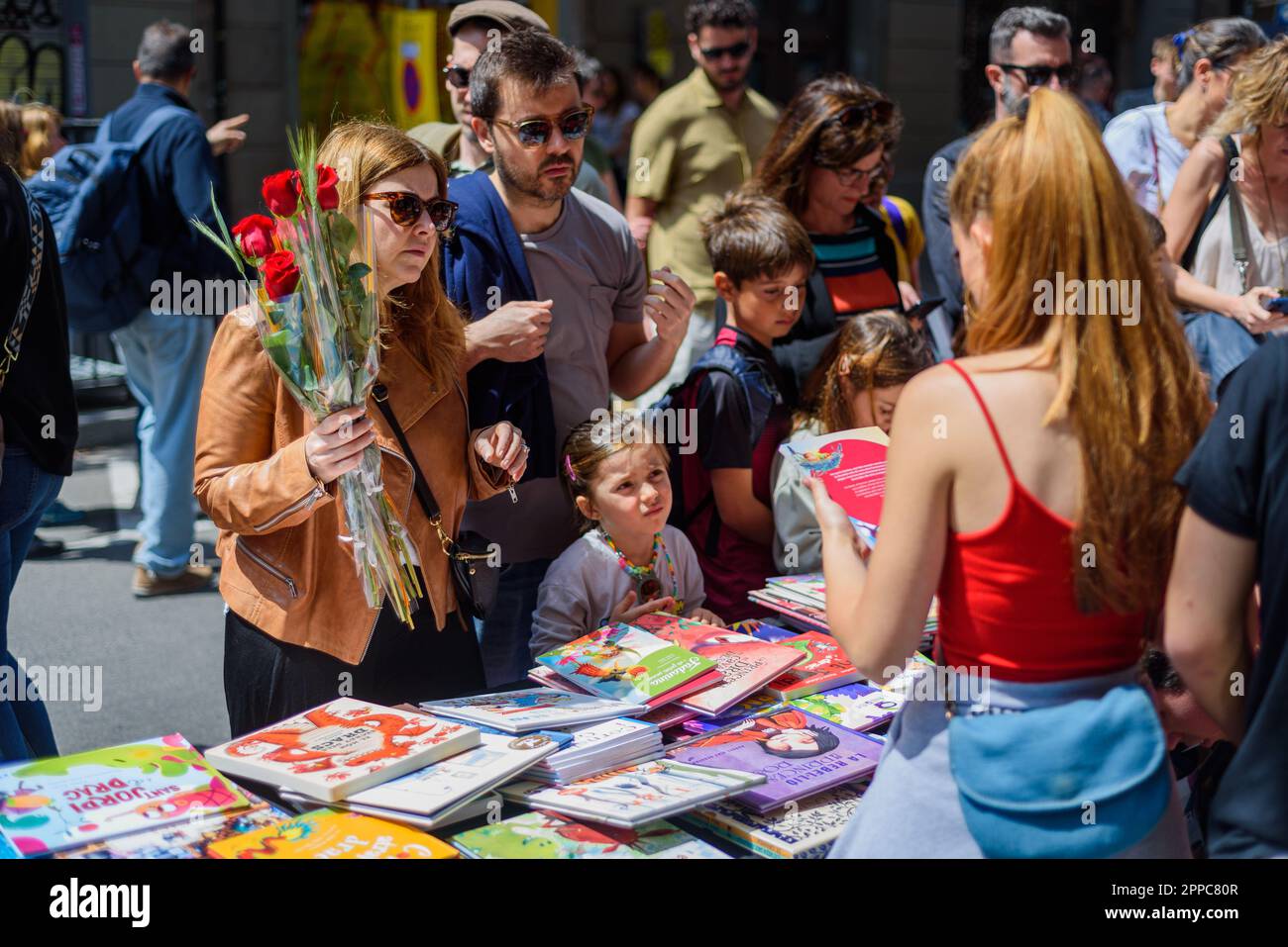 Barcelone, Espagne. 23rd avril 2023. Une famille est vue acheter des livres tout en tenant des roses rouges pendant la fête catalane traditionnelle de Saint George's Day. Ce jour-là, connu sous le nom de « jour de Saint-Georges » (Diada de Sant Jordi en catalan), l'amour et la littérature sont célébrés par la vente de livres et de roses rouges dans tout le pays. Depuis l'année 1997, le slogan officiel de ce jour a été "Une rose pour l'amour, et un livre pour toujours". Crédit : SOPA Images Limited/Alamy Live News Banque D'Images