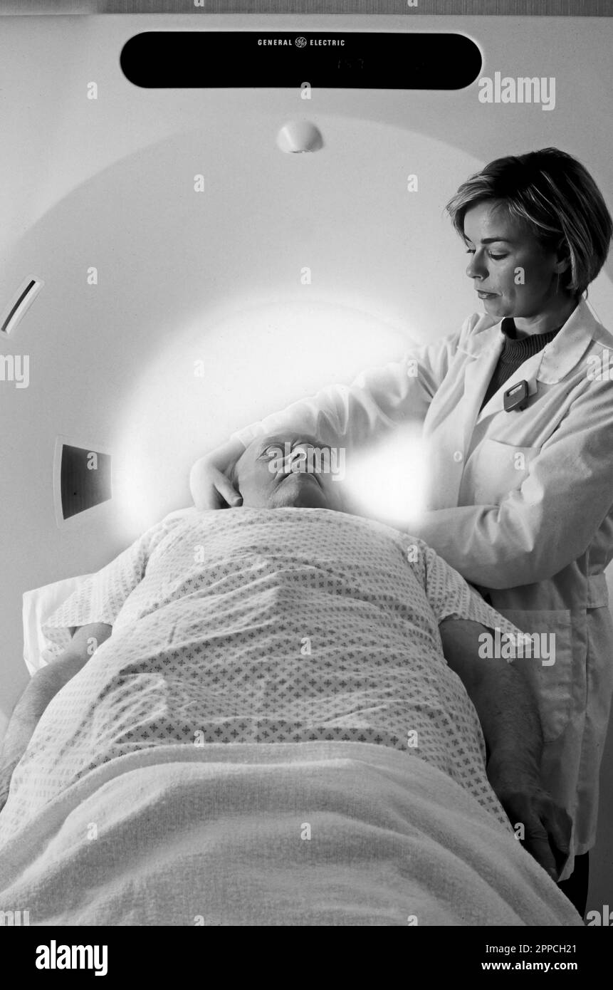 Photo en noir et blanc d'un technicien préparant un homme senior à une IRM Banque D'Images