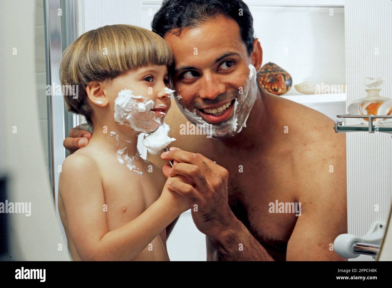 Latino Père prétendant se raser avec son fils dans la salle de bains Banque D'Images