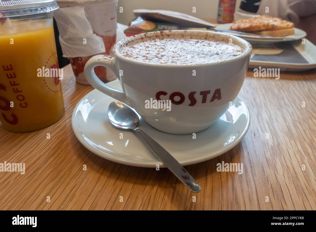 Une tasse de cappuccino dans une tasse sur une sauce dans un café Costa Coffee. Banque D'Images