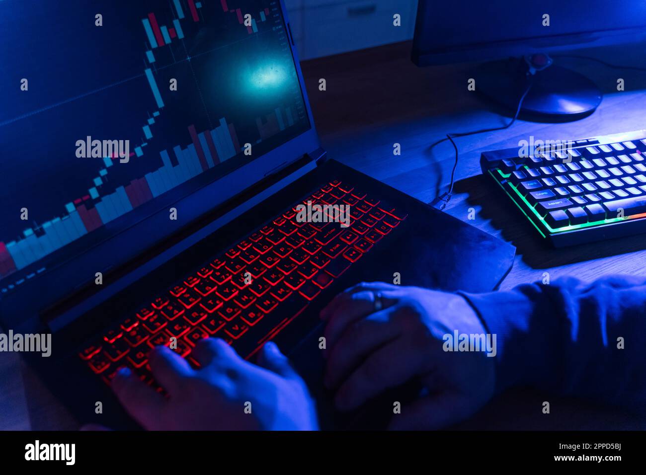 Mains de hacker utilisant le clavier lumineux à la maison Banque D'Images