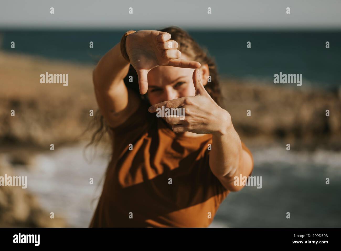 Femme faisant le cadre de doigt à la plage Banque D'Images