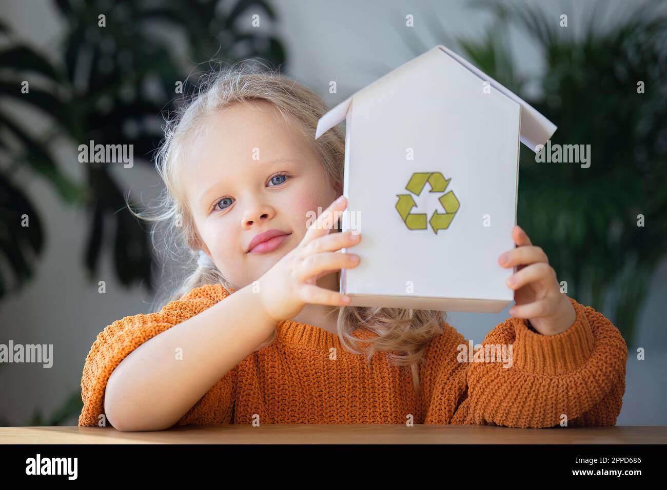 Fille tenant modèle de maison avec le logo de recyclage Banque D'Images