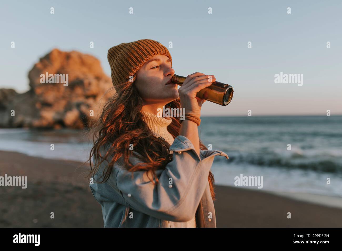 Femme buvant de la bière à la plage Banque D'Images