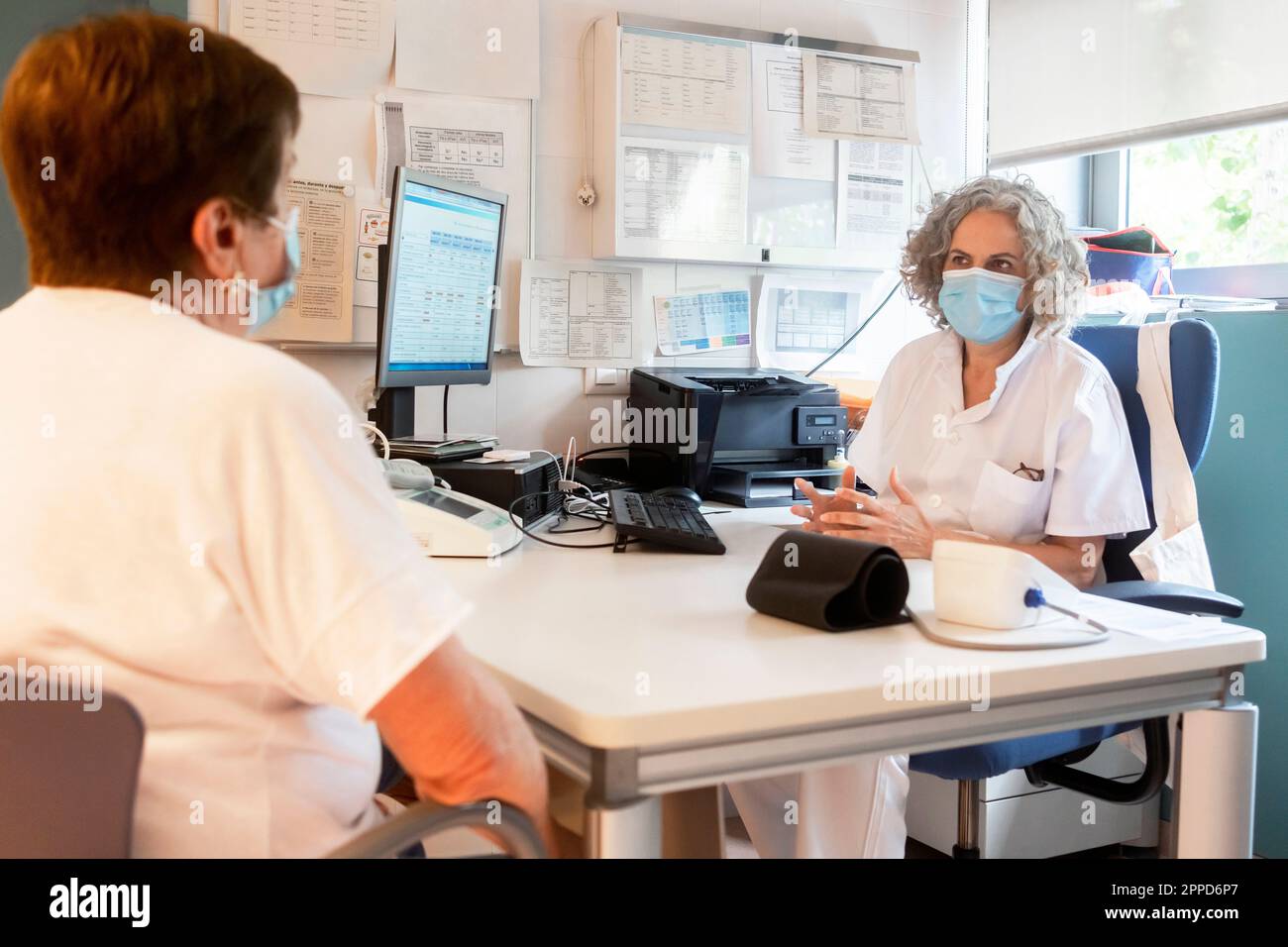Médecin discutant avec le patient senior assis à un bureau dans la clinique Banque D'Images