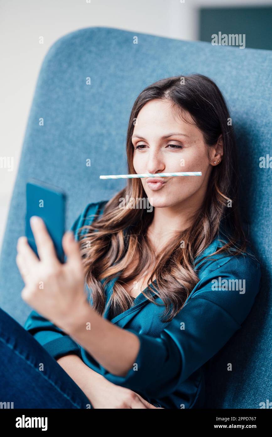 Jeune femme tenant la paille sur les lèvres et prenant le selfie Banque D'Images