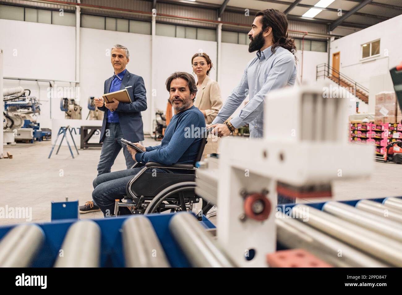 Homme d'affaires avec des collègues qui examinent des machines en usine Banque D'Images