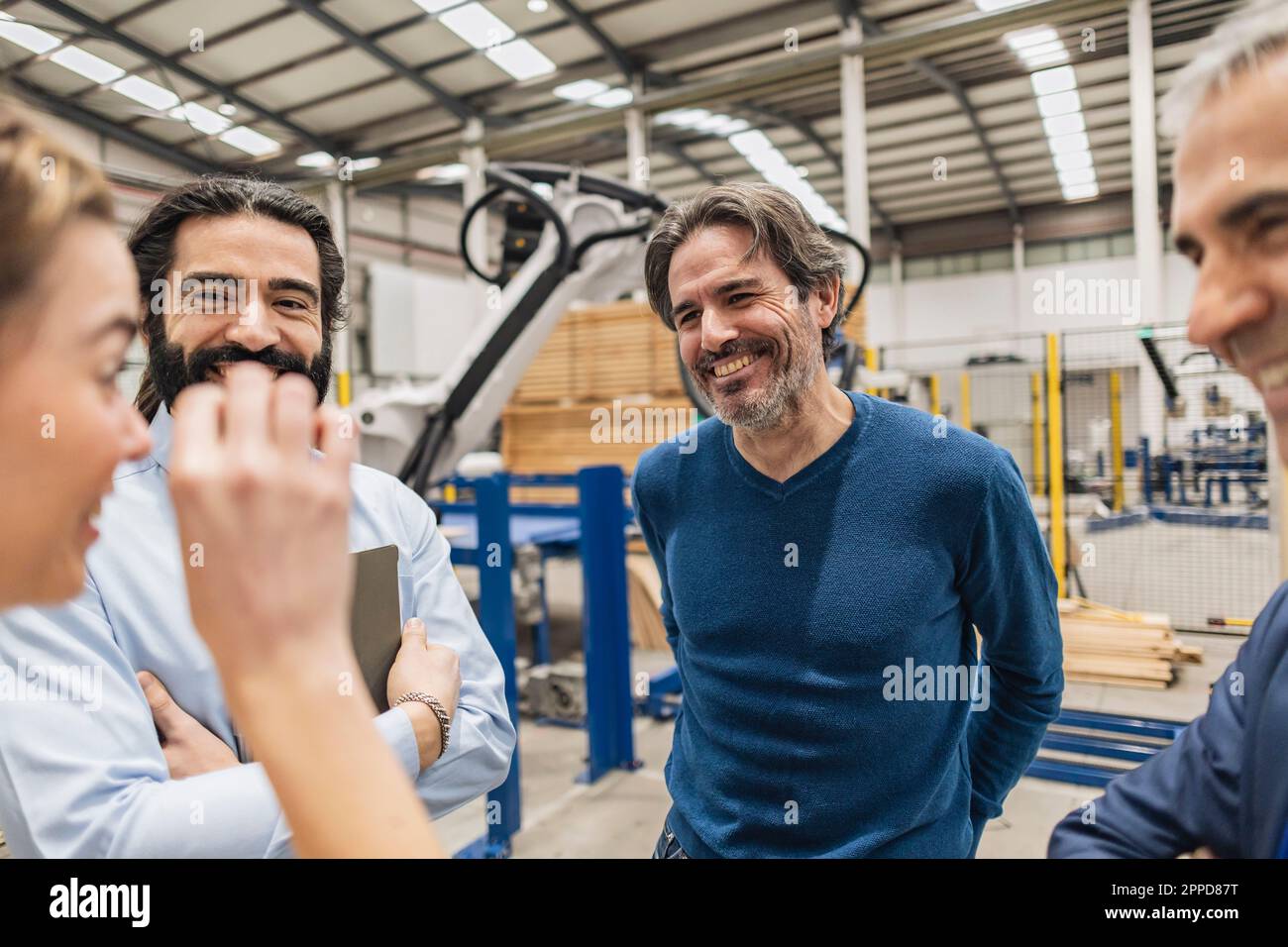 Un jeune ingénieur heureux qui fait des gestes et qui discute en usine Banque D'Images