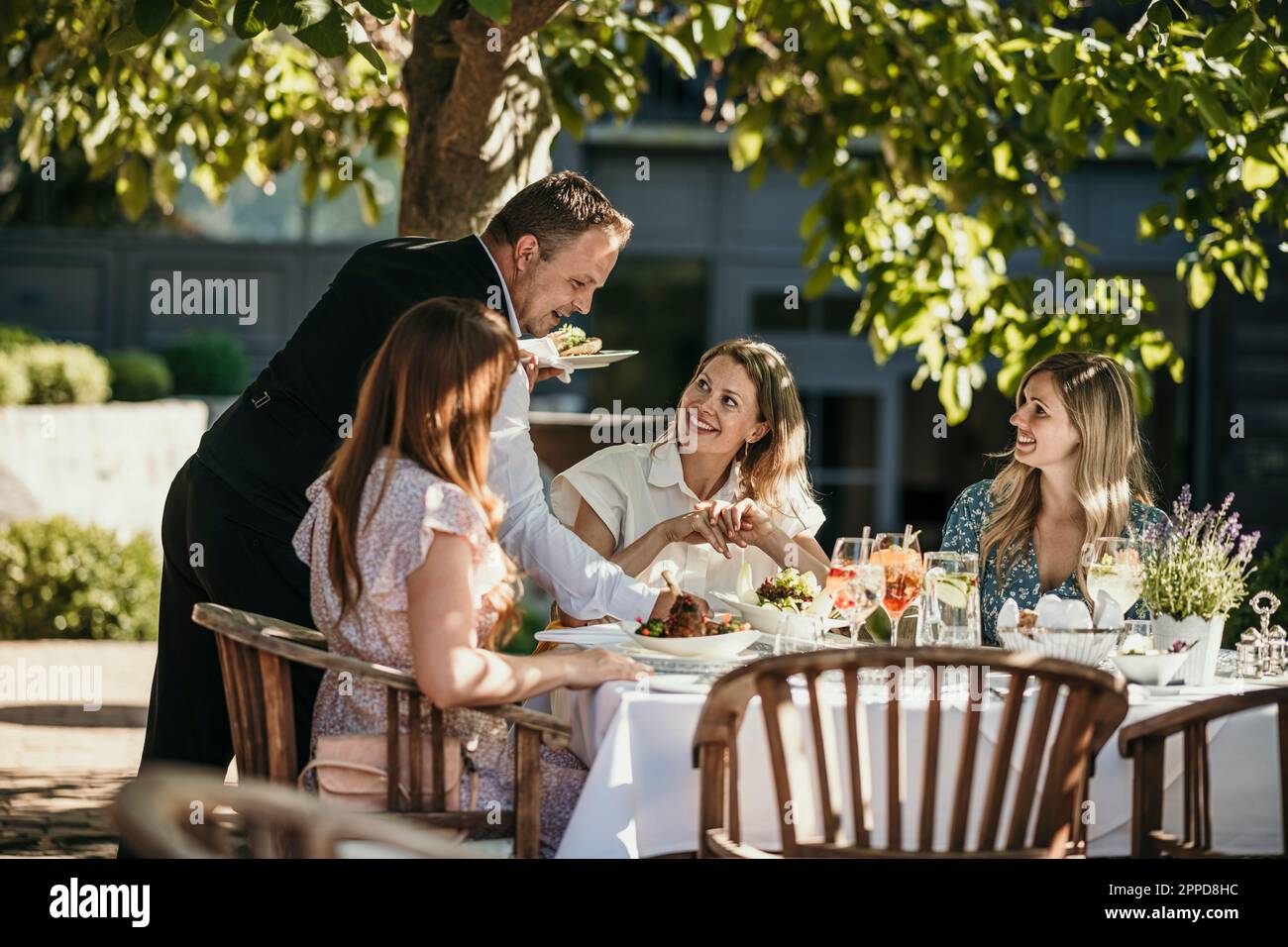 Serveur servant de la nourriture aux femmes au restaurant Banque D'Images