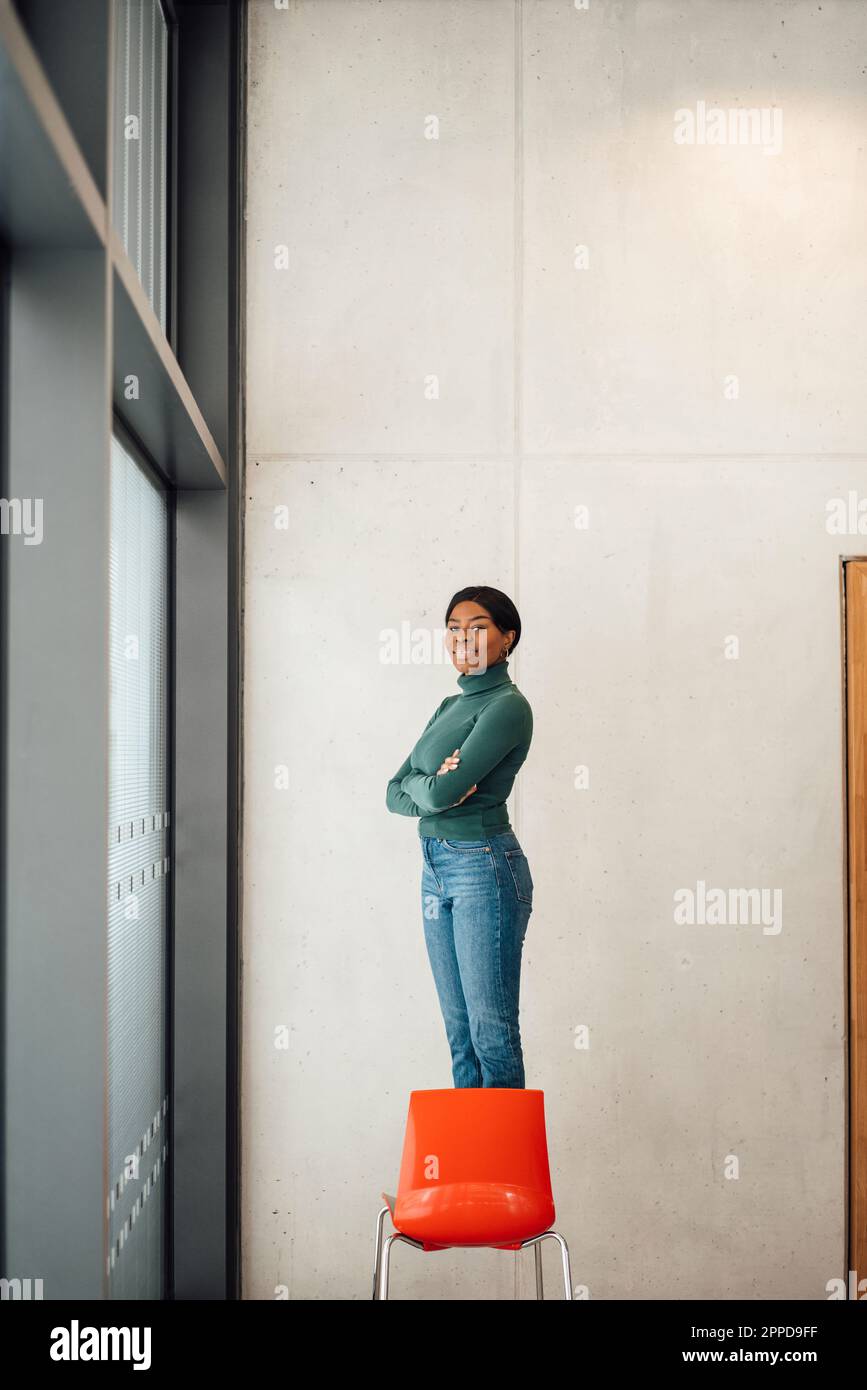 Jeune femme aux bras croisés debout sur la chaise Banque D'Images