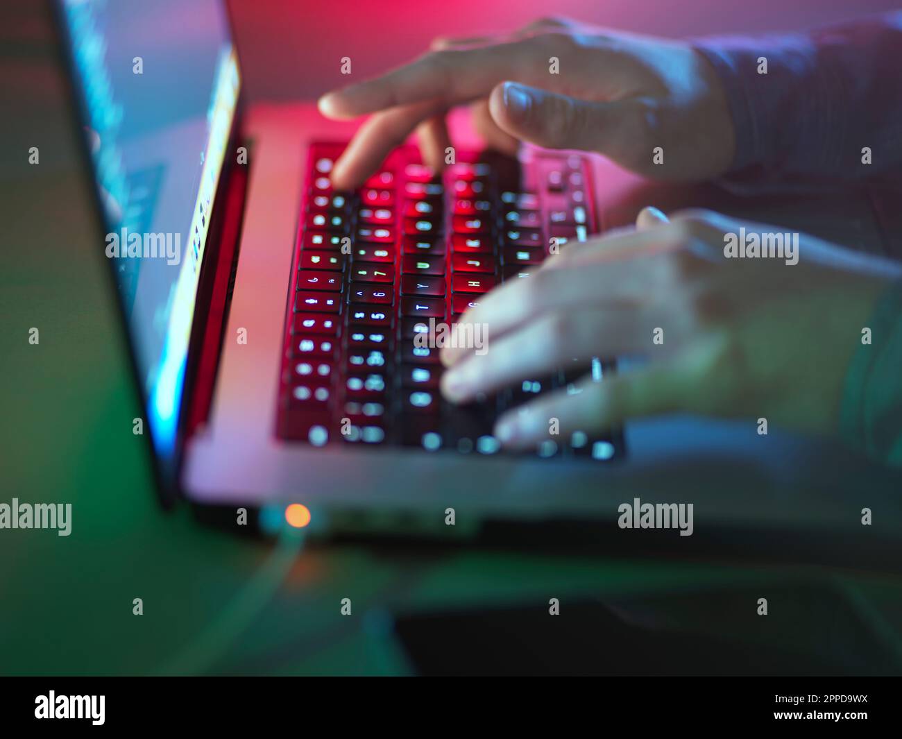 Hacker tapant sur clavier lumineux pour ordinateur portable au bureau Banque D'Images