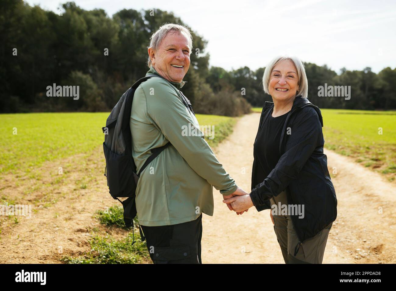 Couple senior de randonnée heureux tenant les mains dans la nature Banque D'Images