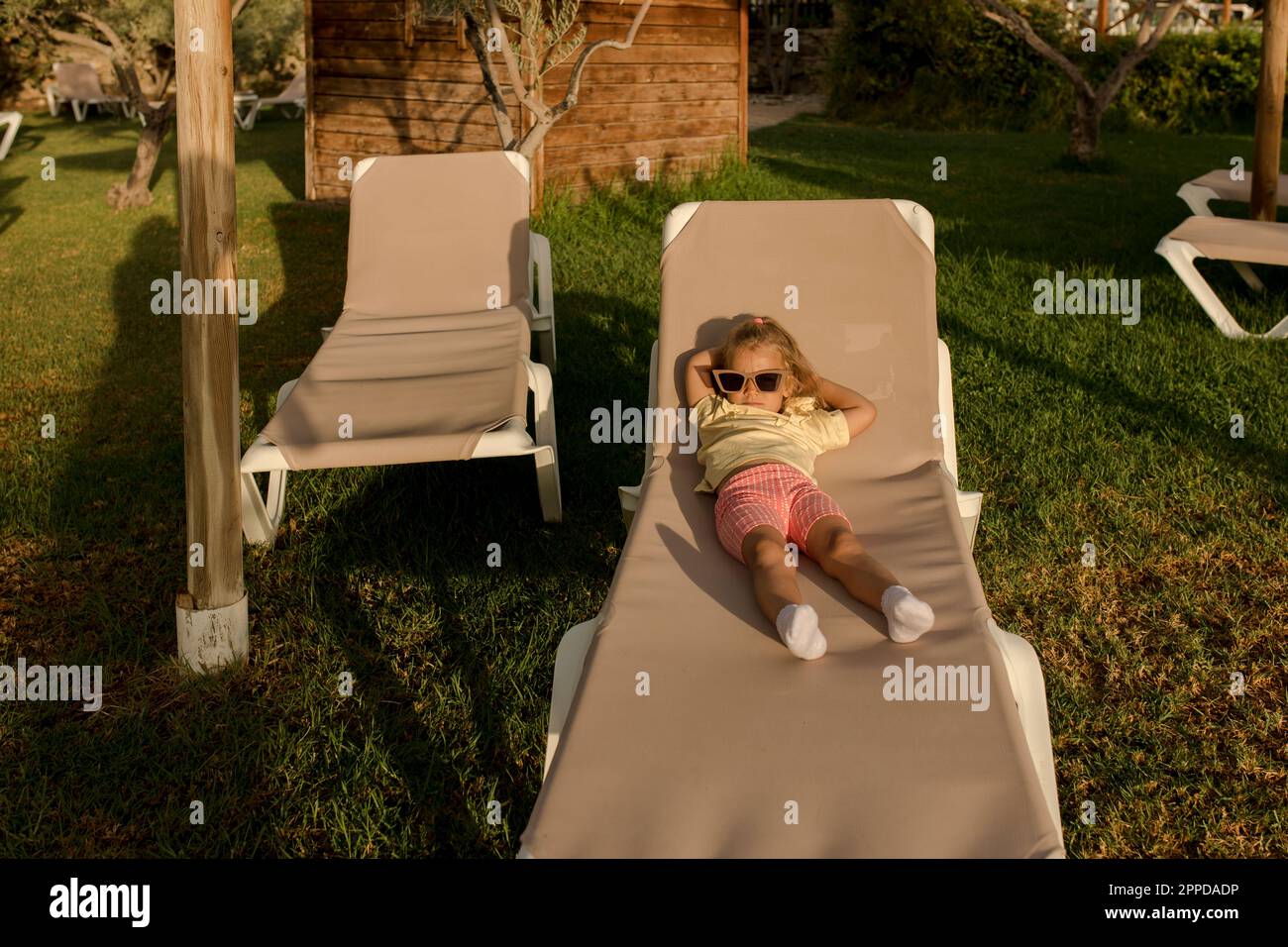 Jolie fille portant des lunettes de soleil couchée sur une chaise longue Banque D'Images