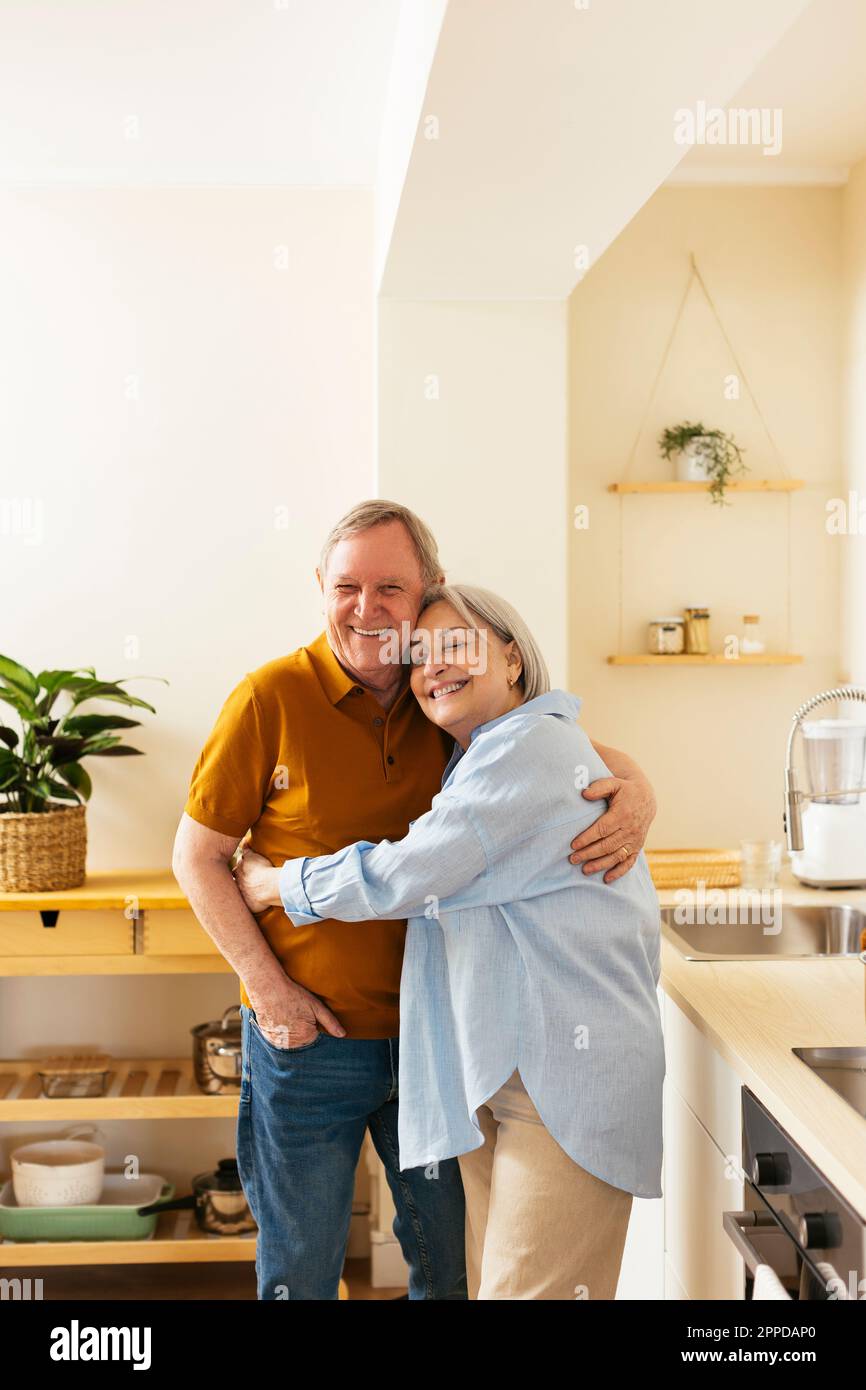 Couple senior affectueux qui s'embrasse dans la cuisine Banque D'Images