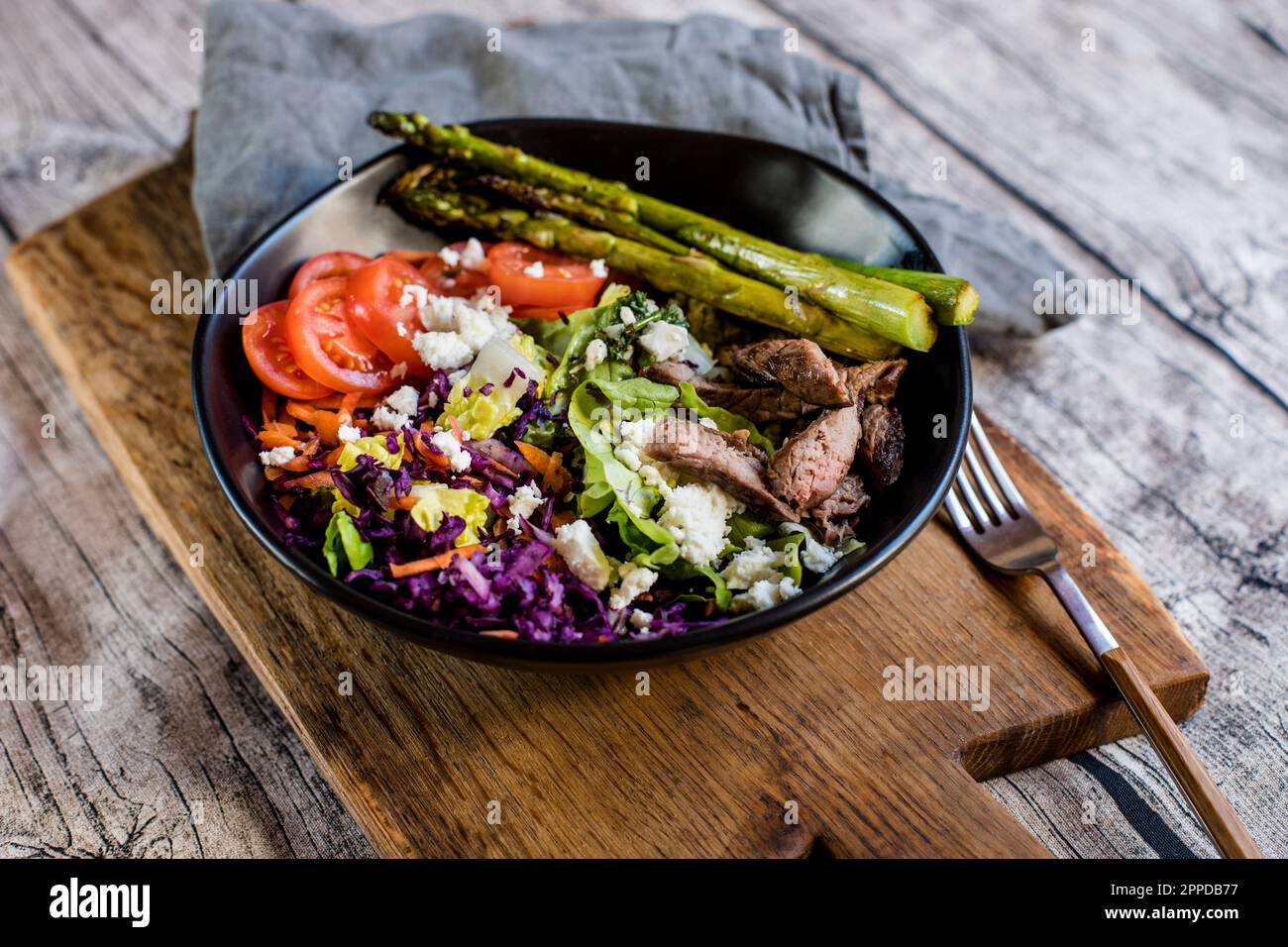 Bol de salade avec steak, asperges, tomates, choux rouges déchiquetés, laitue et feta Banque D'Images