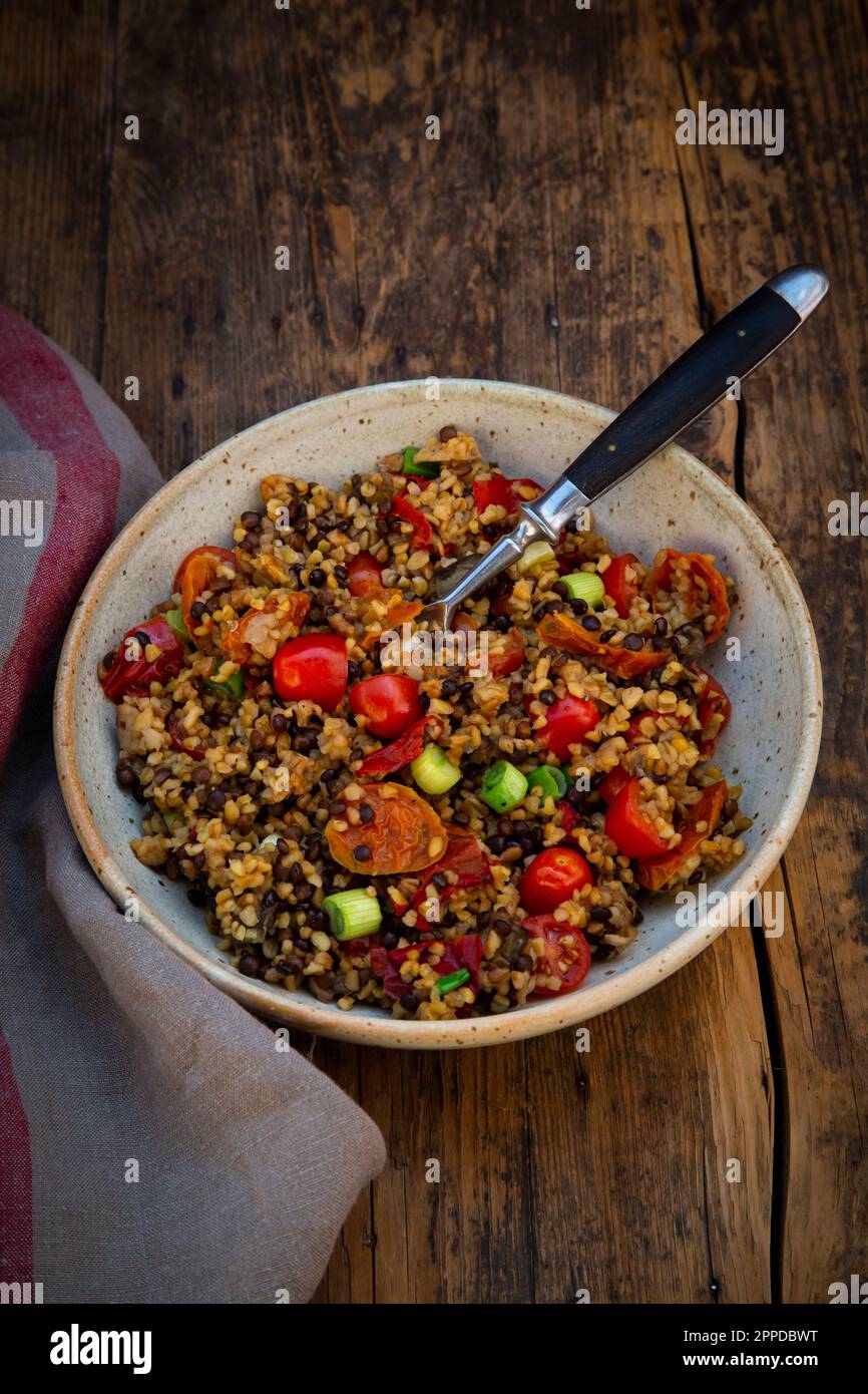 Bol de lentilles de béluga avec bulgur, tomates, poivrons, aubergine et scallion Banque D'Images