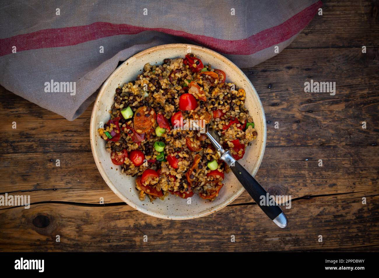 Bol de lentilles de béluga avec bulgur, tomates, poivrons, aubergine et scallion Banque D'Images