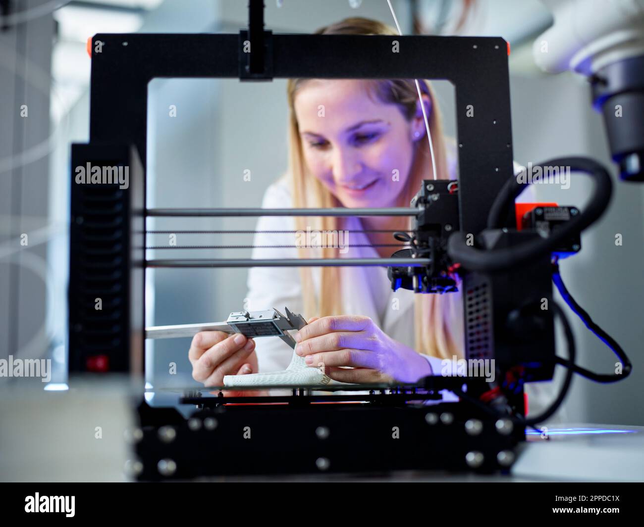 Ingénieur souriant avec pied à coulisse faisant fonctionner la machine à imprimer 3D Banque D'Images